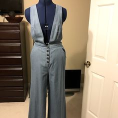 Light Blue Denim Wide Leg Jumpsuit With Side Pockets. Washed Blue Fitted Overalls, Fitted Light Wash Pants For Work, Blue Denim Jumpsuit With Button Closure For Day Out, Blue High Waist Denim Jumpsuit For Work, Chic Blue Wide Leg Overalls, Blue High-rise Jumpsuits And Rompers With Button Closure, Blue High Rise Jumpsuits And Rompers With Button Closure, Blue High Rise Jumpsuit With Button Closure, Workwear Medium Wash Overall Bottoms