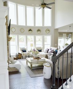 a living room filled with white furniture and lots of windows on the wall above it