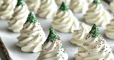 white frosted christmas trees are lined up on a baking sheet with green and red sprinkles