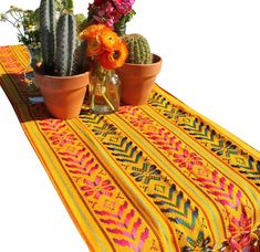 two potted plants sitting on top of a table next to a vase filled with flowers