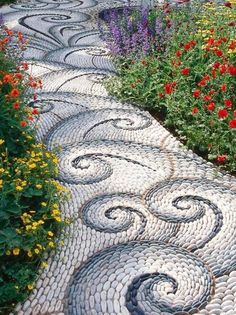 a garden path made out of cobblestones with flowers in the backgroud