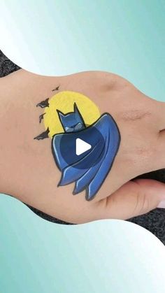 a person's hand with a batman tattoo on it