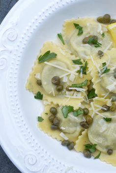 a white plate topped with ravioli and capers