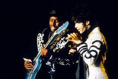 two men standing next to each other holding guitars