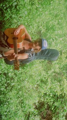 a man sitting in the grass with his guitar