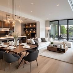 a living room filled with furniture next to a kitchen and dining room table in front of a large window