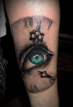 a tattoo with an eye and clock parts on the arm, which is painted blue