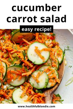 cucumber carrot salad in a white bowl with a wooden spoon on the side