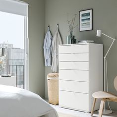 a white dresser sitting next to a bed in a bedroom