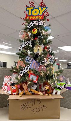 an office cubicle with a christmas tree and toys on the desk in front of it