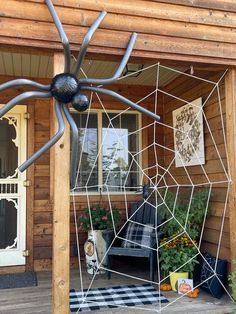 a large spider web sculpture sitting on top of a wooden porch next to a door