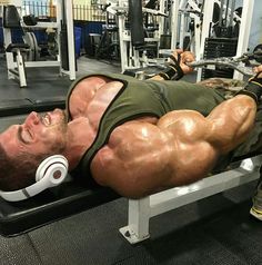 a man laying on top of a bench with headphones in his ears while working out