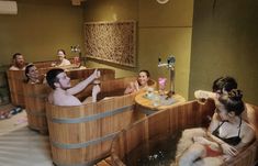 a group of people sitting inside of a wooden bath tub