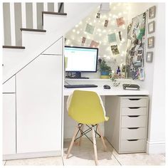 a desk with a computer on top of it next to a stair case filled with pictures