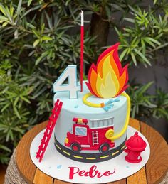 a birthday cake with a firetruck and number four on the top is sitting on a wooden table