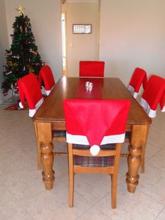 a wooden table topped with red chairs next to a christmas tree