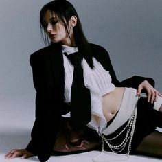 a woman sitting on the ground wearing a suit and tie with chains around her ankles