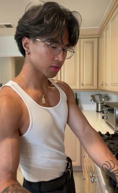 a man wearing glasses standing in front of an oven with his arm wrapped around the stove