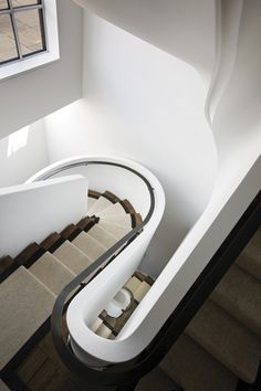 an aerial view of a spiral staircase in a building with white walls and brown flooring