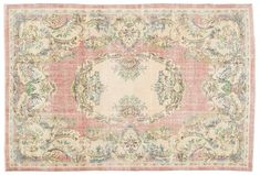 an antique rug with pink and green floral designs on the bottom, in pastel tones