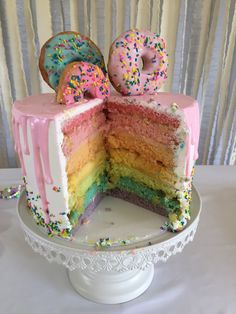 a rainbow cake with two donuts on top