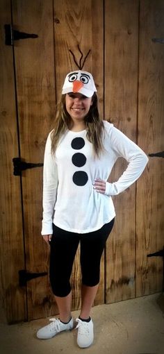 a woman wearing a white shirt and black leggings standing in front of a wooden door