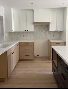 an empty kitchen with white cabinets and wood floors