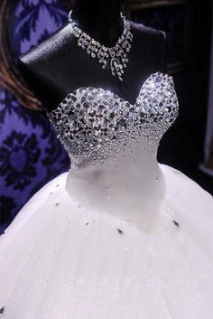 a white dress on display in front of a mannequin wearing a tiara