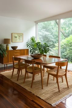 a dining room table with chairs and a potted plant in the middle on top of a rug