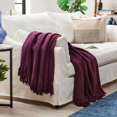 a white couch with a purple blanket on it