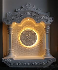 an illuminated clock with the word om on it's face in front of a wall