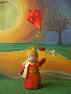 a small doll holding a kite in front of a painting