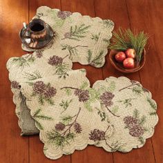 two placemats with pine cones and berries on them sitting on a wooden floor