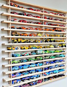 a wooden shelf filled with lots of toy cars on top of it's sides