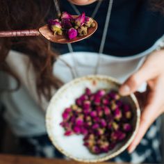 a woman holding a spoon full of flowers