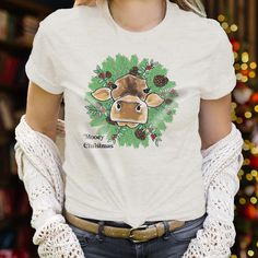 "Mooey Christmas" Unisex short sleeve adult tee Christmas meets the farm life with this totally original design! Made with super soft material, the shirt pairs fun artwork with lightweight comfort, perfect for layering under a flannel or sweater this holiday season.  Sizes available include: Unisex XS, Unisex S, Unisex M, Unisex L, Unisex XL, Unisex 2XL **Clothing has been reviewed as true to size. WHAT MAKES US DIFFERENT? - Our clothing is inspired by realistic images of the things our kids LOVE. From tractors to chickens to mountains and forests, we strive to create unique illustrations for babies and kids of all ages.  - Our clothing is made with a polyester/cotton blend that is SUPER SOFT and won't shrink the moment it is put in the dryer! - We are a family business! All clothing is de Mooey Christmas, Fun Artwork, Cow Christmas, Christmas Farm, Farm Cow, Holiday Apparel, Country Western, Christmas 2024, Family Business