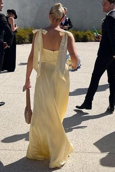 a woman in a yellow dress walking down the street