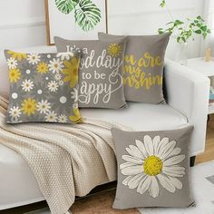 three pillows on a white couch with yellow and gray flowers in the middle, one has a quote that says i'm today to be happy