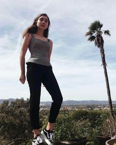 a woman standing on top of a rock next to a palm tree in the desert