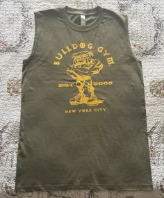 BULLDOG GYM New York City Sleeveless Shirt. Brand New without Tag. 100% Cotton. Color: Army Green / Vintage Gold. Sizes Available: Medium, Large, Extra Large. Please check my other Bulldog Gym listings for additional Styles, Colors and Designs. Shipping fees: $3.99 (the 50 states), $9.99 (Canada), $14.99 (Worldwide). Thank you for looking. Vintage Gym Shirt, Dogpound Gym, Vintage Gym, The 50 States, Muscle Shirt, Golds Gym, Muscle T Shirts, Muscle Shirts, Green Vintage