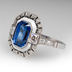 This fabulous Art Deco inspired ring is centered with one (1) cut-cornered rectangular cut natural sapphire that is bordered with white enamel. The ring is accented with two (2) square French cut diamonds, and twenty-two (22) bead set round brilliant and old European cut diamonds. The ring is bordered with milgrain edging. It measures 16.2mm at the top, rises 6.8mm above the finger, tapering to 1.9mm wide and 1.1mm thick at the base of the shank. It is currently a size 7. Elegant Rectangular Enamel Jewelry, White Sapphire Art Deco Jewelry, White Art Deco Baguette Cut Jewelry, White Emerald Cut Art Deco Jewelry, Elegant White Gold Sapphire Ring Rectangular, Elegant White Gold Sapphire Ring With Rectangular Shape, Elegant Rectangular Sapphire Ring In White Gold, Elegant White Gold Rectangular Sapphire Ring, Luxury Sapphire Ring With Rectangular Center Stone