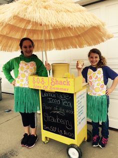 two girls standing under an umbrella selling lemonade