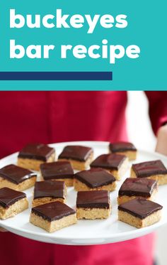 a person holding a white plate with brownies on it and the words buckeyes bar recipe