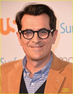 the man is wearing glasses and smiling for the camera with his eyes wide open in front of him