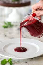 someone pouring red liquid onto a white plate