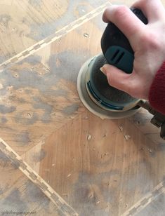 a person using a grinder on wood flooring with the help of a hand