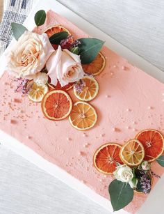 there is a pink cake with orange slices and flowers on it