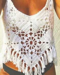 a woman wearing a white crochet top and black shorts