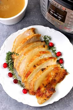 slices of chicken on a plate with cranberries and herbs next to an instant pressure cooker