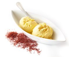 two scoops of ice cream in a white bowl with saffron sprinkles